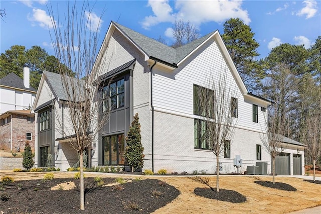 view of side of home featuring a garage, central AC, and brick siding