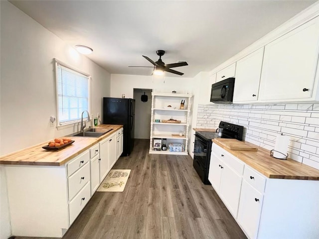 kitchen with black appliances, butcher block countertops, a sink, and white cabinetry