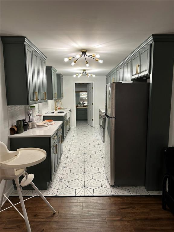 kitchen featuring gray cabinets, stainless steel fridge, sink, and a chandelier