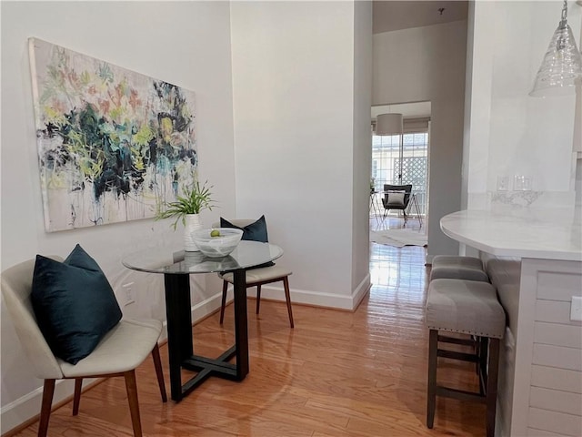 dining space featuring baseboards and light wood-type flooring