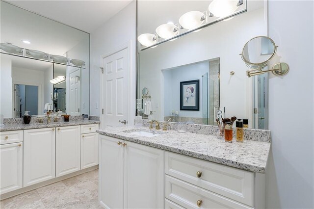 bathroom with a shower with door, a sink, and two vanities