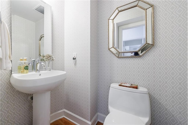 bathroom featuring baseboards, visible vents, wallpapered walls, and toilet