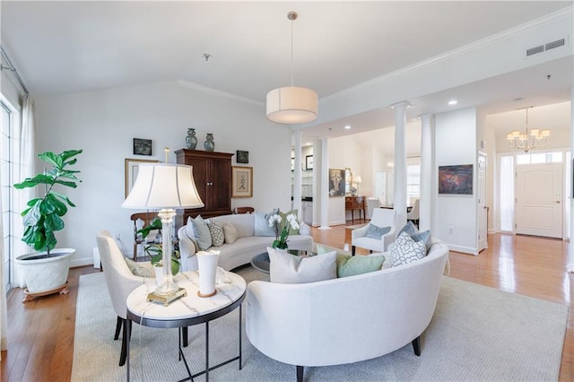 living area featuring lofted ceiling, ornamental molding, baseboards, light wood-style floors, and visible vents