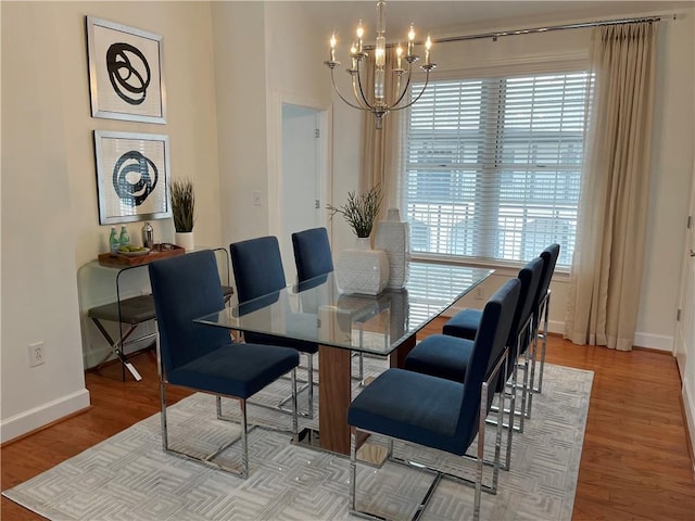 dining space with baseboards, wood finished floors, and a chandelier