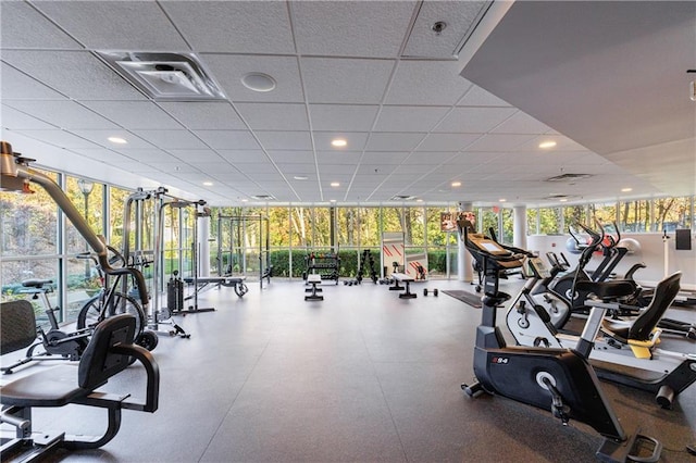 workout area featuring a healthy amount of sunlight, floor to ceiling windows, visible vents, and a drop ceiling