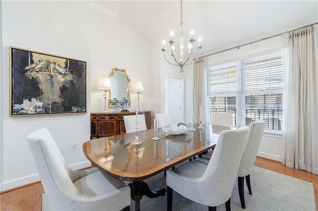 dining space featuring lofted ceiling, baseboards, a chandelier, and wood finished floors