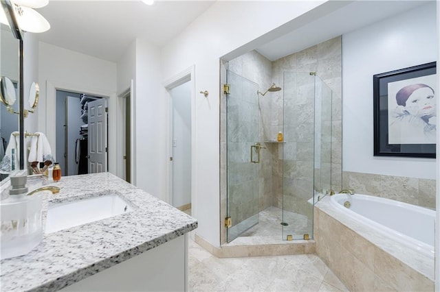 full bath with vanity, a bath, a walk in closet, and a shower stall
