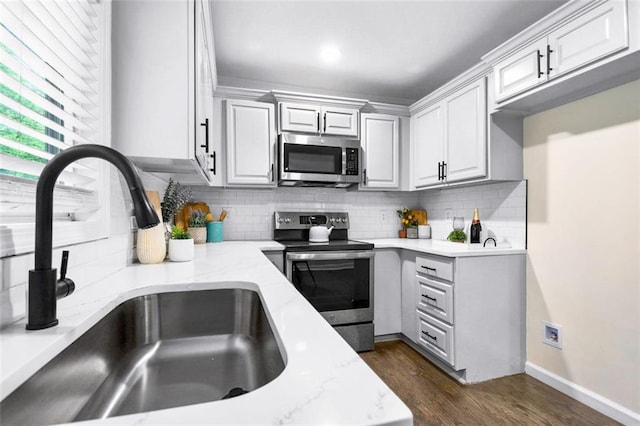 kitchen featuring light stone countertops, sink, dark wood-type flooring, decorative backsplash, and appliances with stainless steel finishes