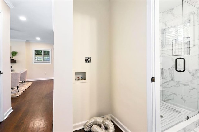 bathroom featuring wood-type flooring, ornamental molding, and a shower with door