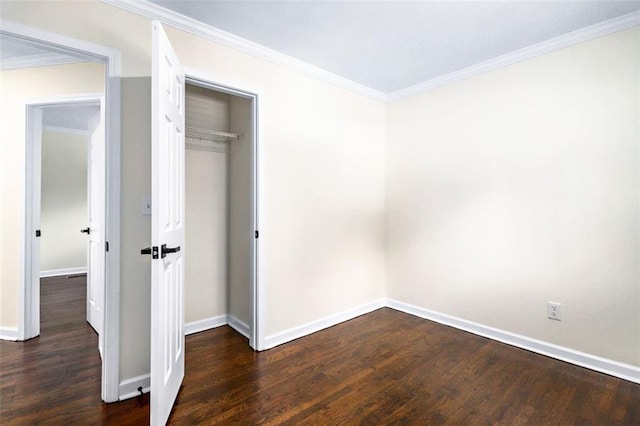 unfurnished bedroom with dark hardwood / wood-style flooring, crown molding, and a closet