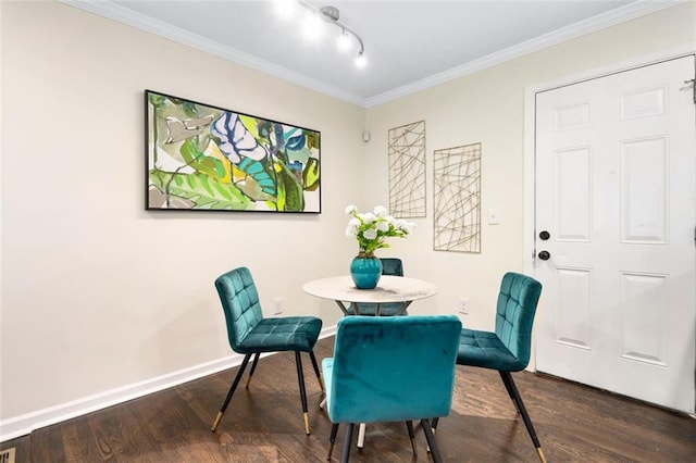 dining space with dark hardwood / wood-style flooring, ornamental molding, and track lighting