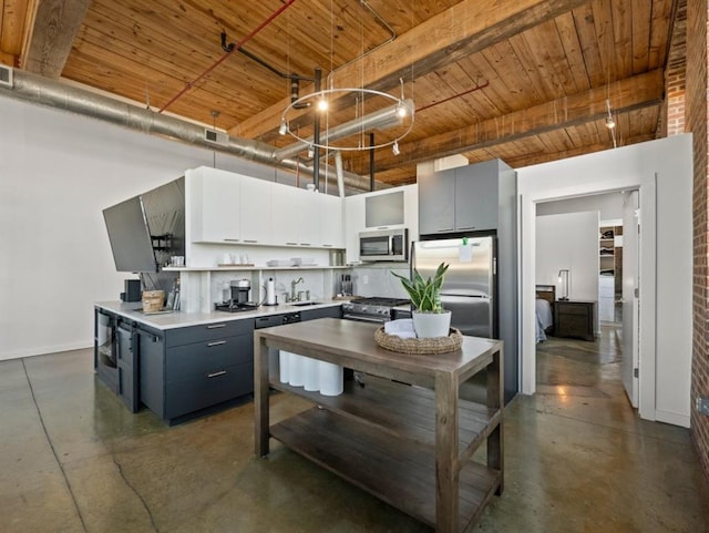 kitchen with a sink, appliances with stainless steel finishes, finished concrete flooring, and gray cabinets