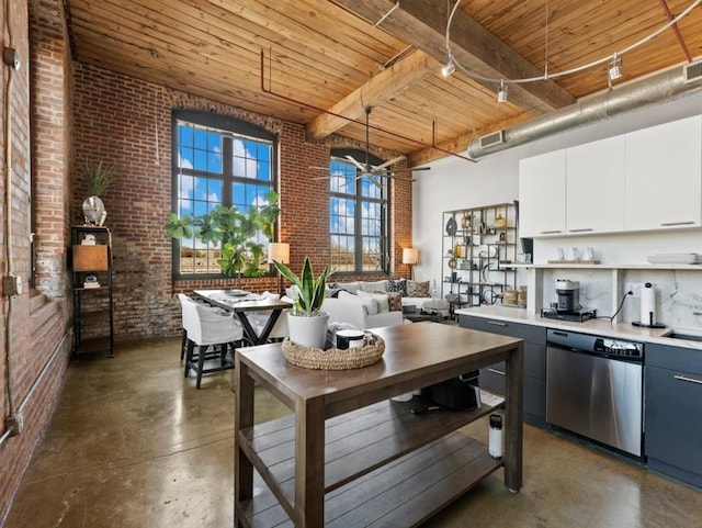 kitchen featuring stainless steel dishwasher, concrete flooring, and brick wall