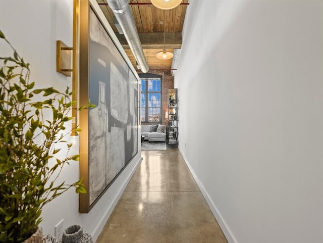 hallway with wood ceiling, baseboards, and concrete floors