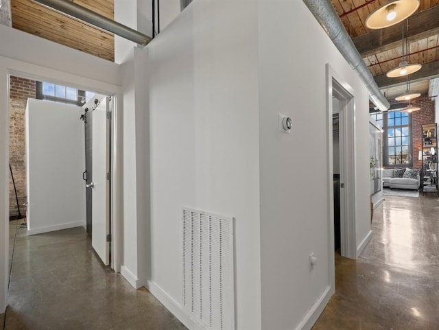 hall featuring visible vents, baseboards, finished concrete floors, wooden ceiling, and a high ceiling