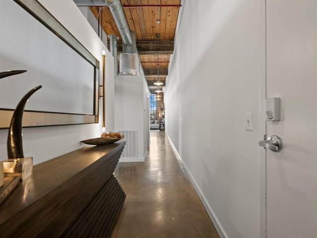 hall with visible vents, baseboards, finished concrete floors, and wooden ceiling