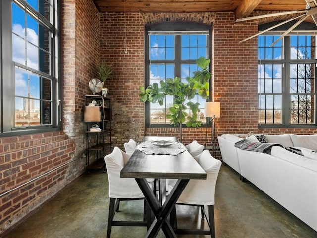 dining room featuring finished concrete floors, brick wall, and a towering ceiling