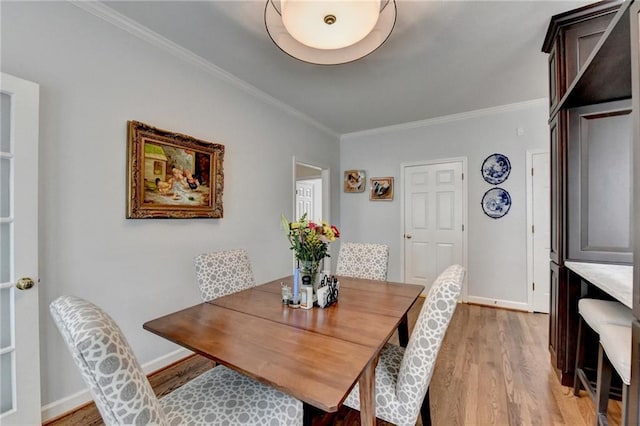 dining space featuring light wood-type flooring, crown molding, and baseboards