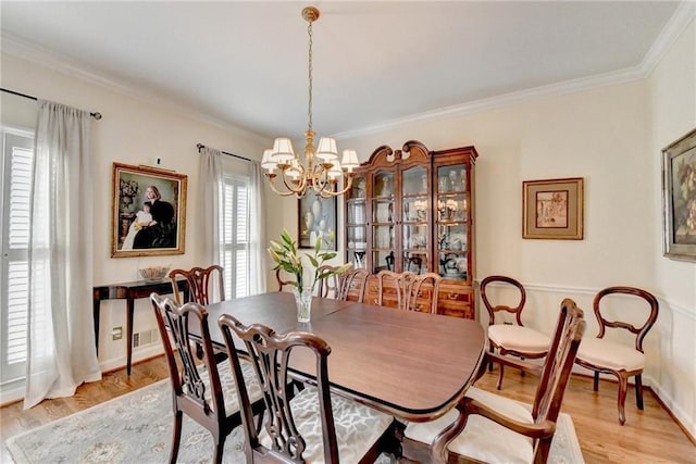 dining area featuring baseboards, ornamental molding, light wood-style flooring, and a notable chandelier