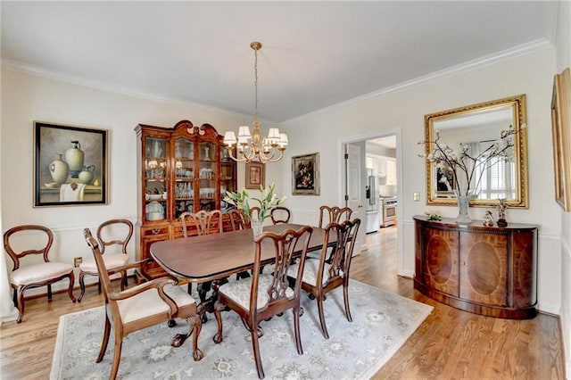 dining space with light wood finished floors, crown molding, and a notable chandelier