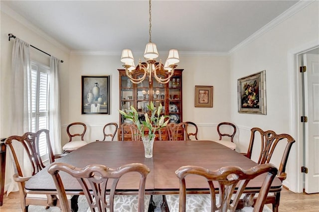 dining area featuring light wood-style floors, crown molding, and an inviting chandelier