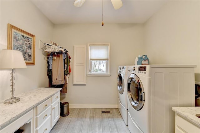 washroom featuring separate washer and dryer, visible vents, baseboards, light wood-type flooring, and cabinet space