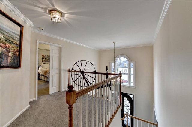 hallway featuring ornamental molding, carpet flooring, an upstairs landing, and baseboards