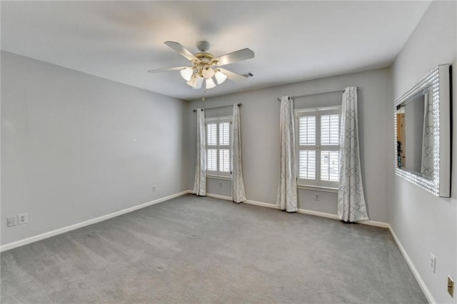 carpeted spare room with ceiling fan, visible vents, and baseboards