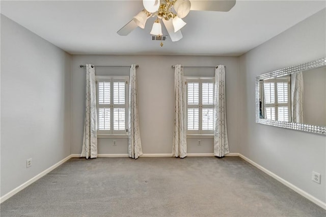 carpeted spare room with a ceiling fan, visible vents, and baseboards