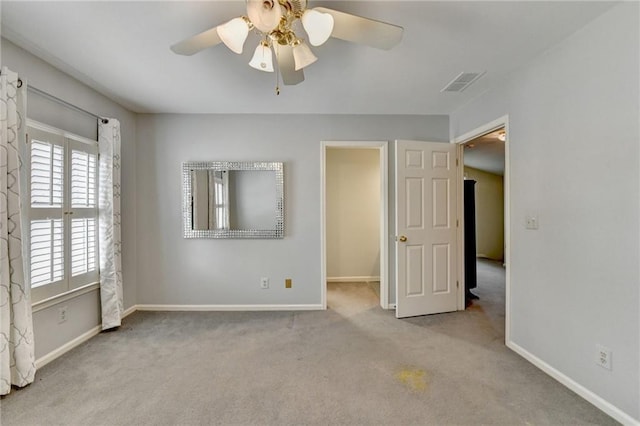 carpeted empty room with a ceiling fan, visible vents, and baseboards