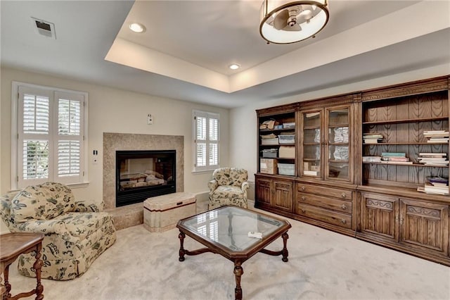 living area featuring a tray ceiling, carpet, recessed lighting, visible vents, and a premium fireplace