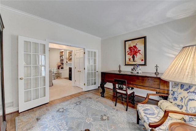 living area with wood finished floors, visible vents, baseboards, ornamental molding, and french doors