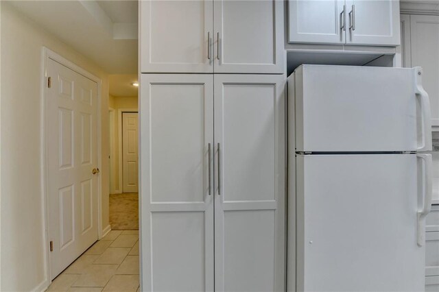 kitchen with white cabinetry, light tile patterned flooring, and freestanding refrigerator