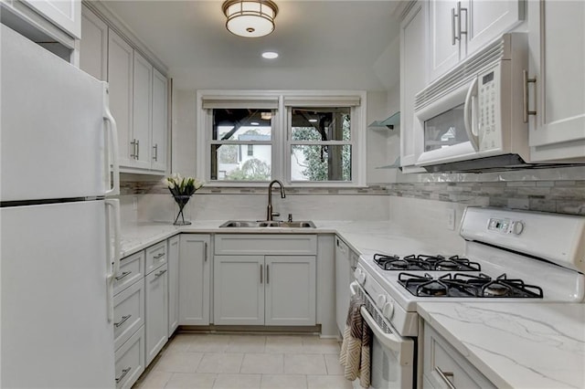 kitchen with light stone counters, white appliances, a sink, and decorative backsplash