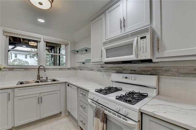 kitchen featuring white appliances, light tile patterned flooring, a sink, and decorative backsplash