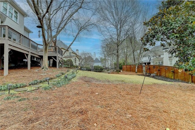 view of yard featuring a deck, fence, and stairs