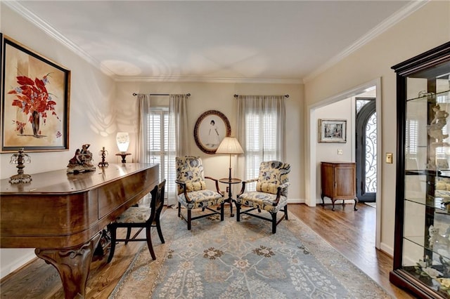 sitting room with ornamental molding, wood finished floors, and baseboards