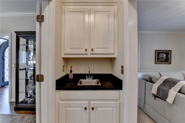 bar with ornamental molding, wet bar, a sink, and wood finished floors