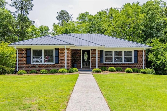 view of front of property featuring a front yard, metal roof, and brick siding