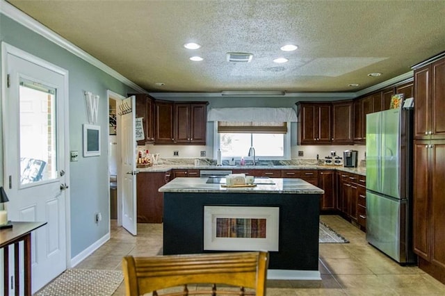 kitchen with freestanding refrigerator, a textured ceiling, crown molding, a center island, and a sink