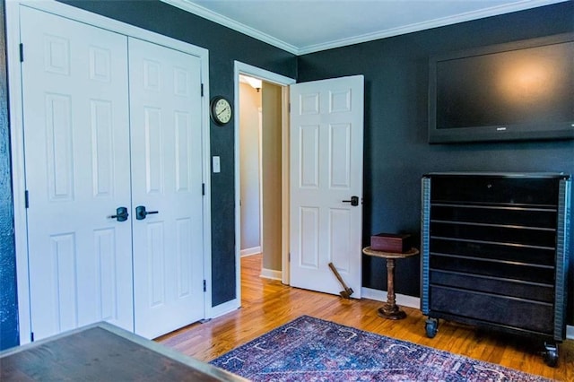 bedroom with wood finished floors, a closet, ornamental molding, and baseboards