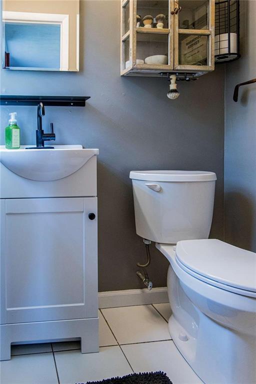 half bath with tile patterned floors, toilet, vanity, and baseboards