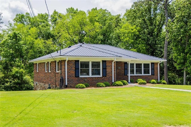 view of front of house with a front lawn, brick siding, and metal roof