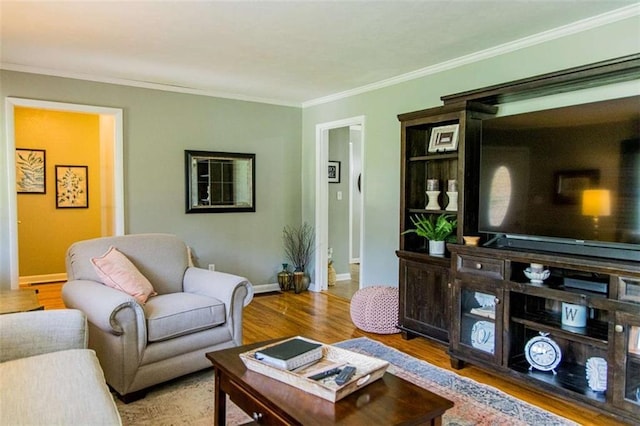 living area with wood finished floors, ornamental molding, and baseboards