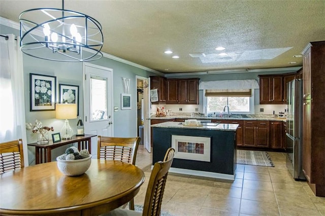 kitchen with crown molding, a sink, freestanding refrigerator, light countertops, and dark brown cabinets