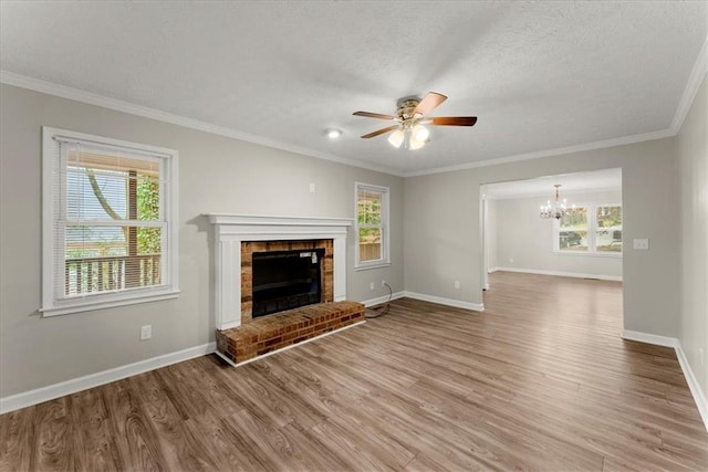 unfurnished living room with hardwood / wood-style floors, ceiling fan with notable chandelier, ornamental molding, a fireplace, and a textured ceiling