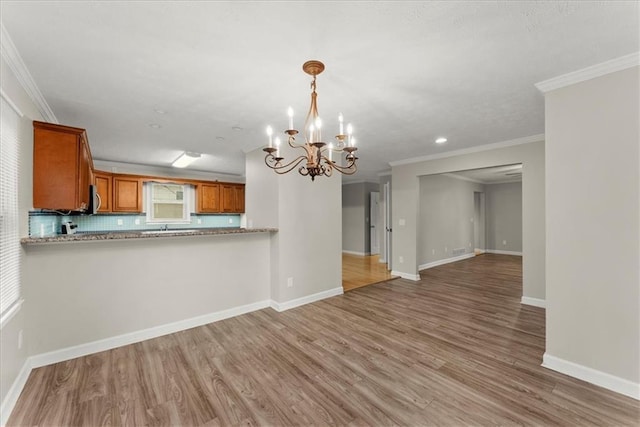 kitchen with tasteful backsplash, light hardwood / wood-style flooring, a notable chandelier, kitchen peninsula, and crown molding