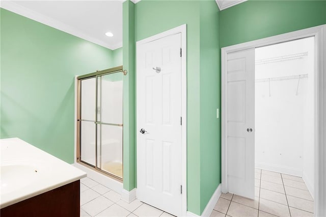 bathroom featuring tile patterned floors, vanity, a shower with shower door, and ornamental molding