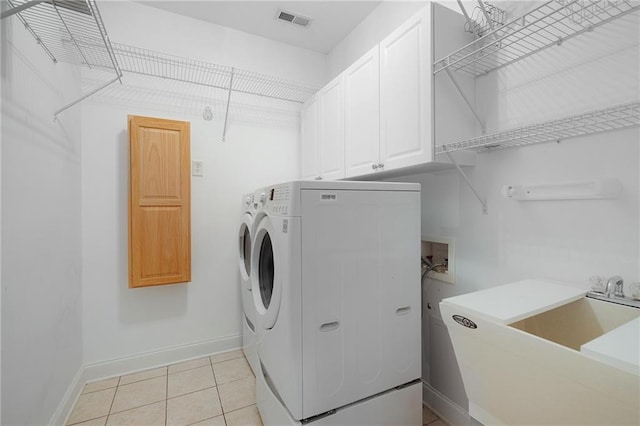 clothes washing area featuring cabinets, light tile patterned floors, separate washer and dryer, and sink