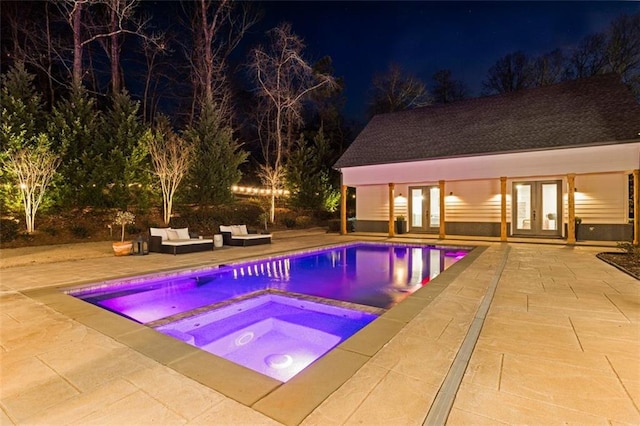 pool at twilight featuring an outbuilding, an outdoor living space, an in ground hot tub, and a patio area